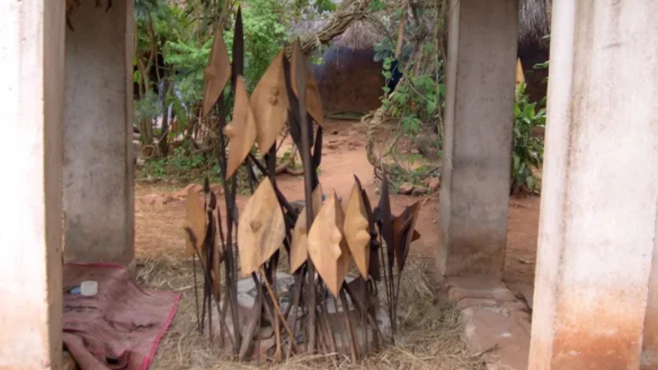 Sacred shrine courtyard with ancestral clay totems and ceremonial spears
